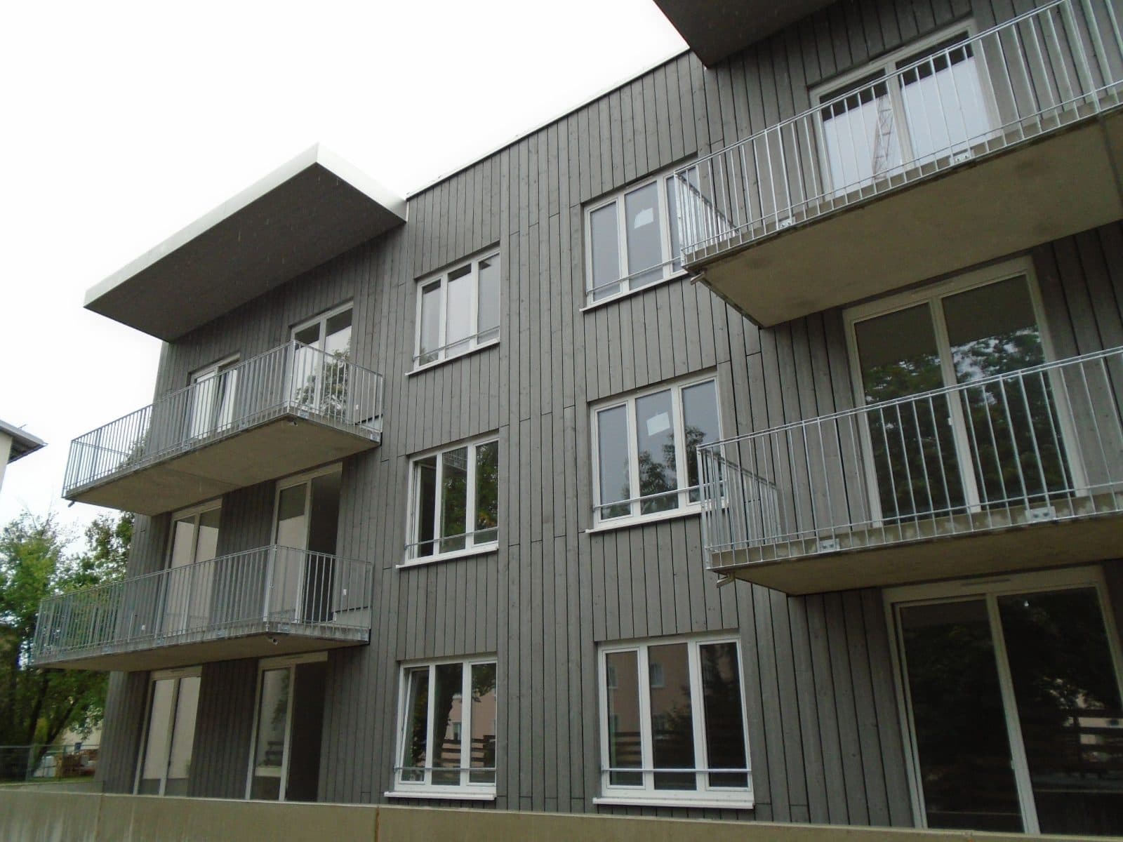 Mehrere Metallbalkone an einer Holzfassade