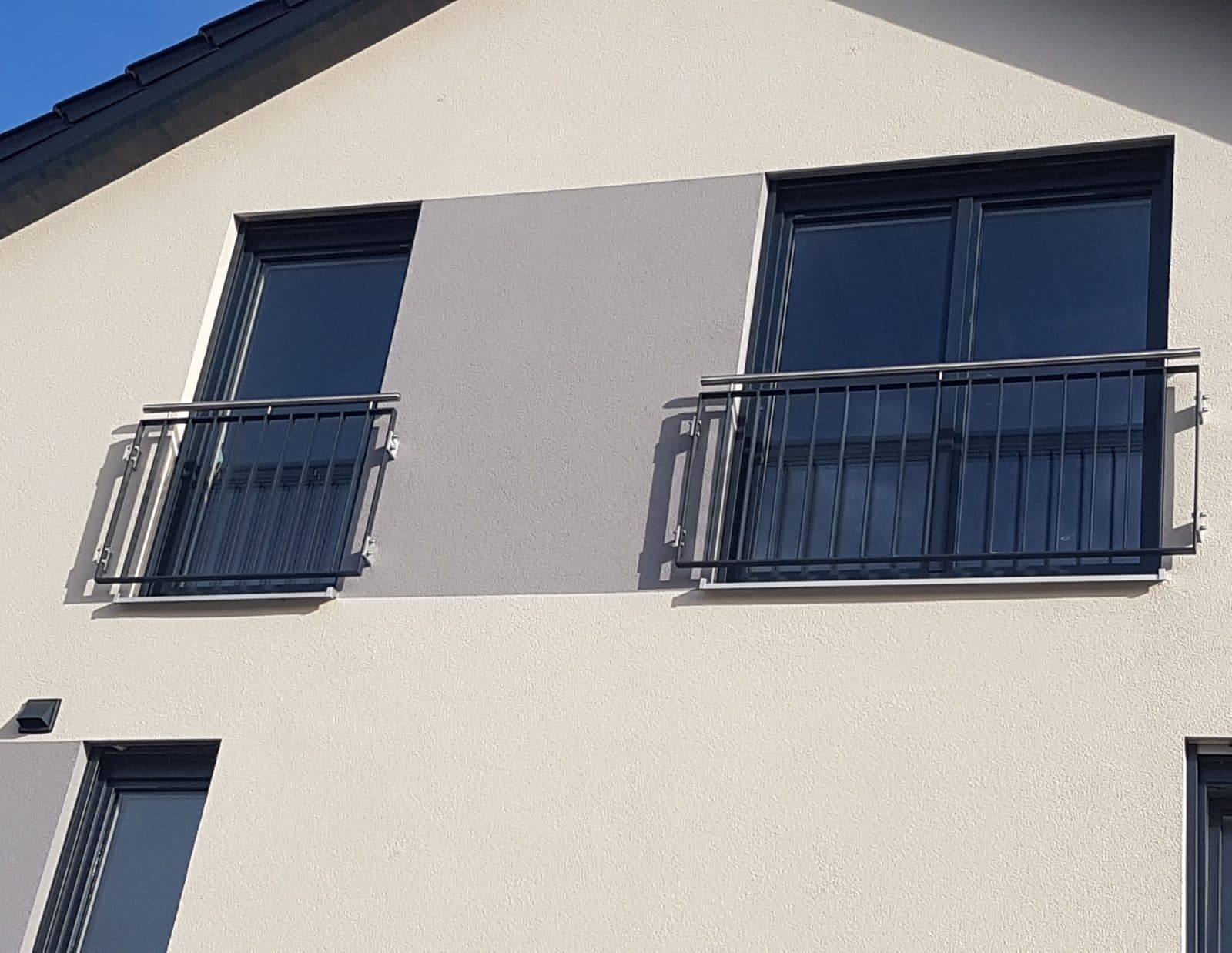 Zwei französische Balkone aus Metall an einer hellen Fassade