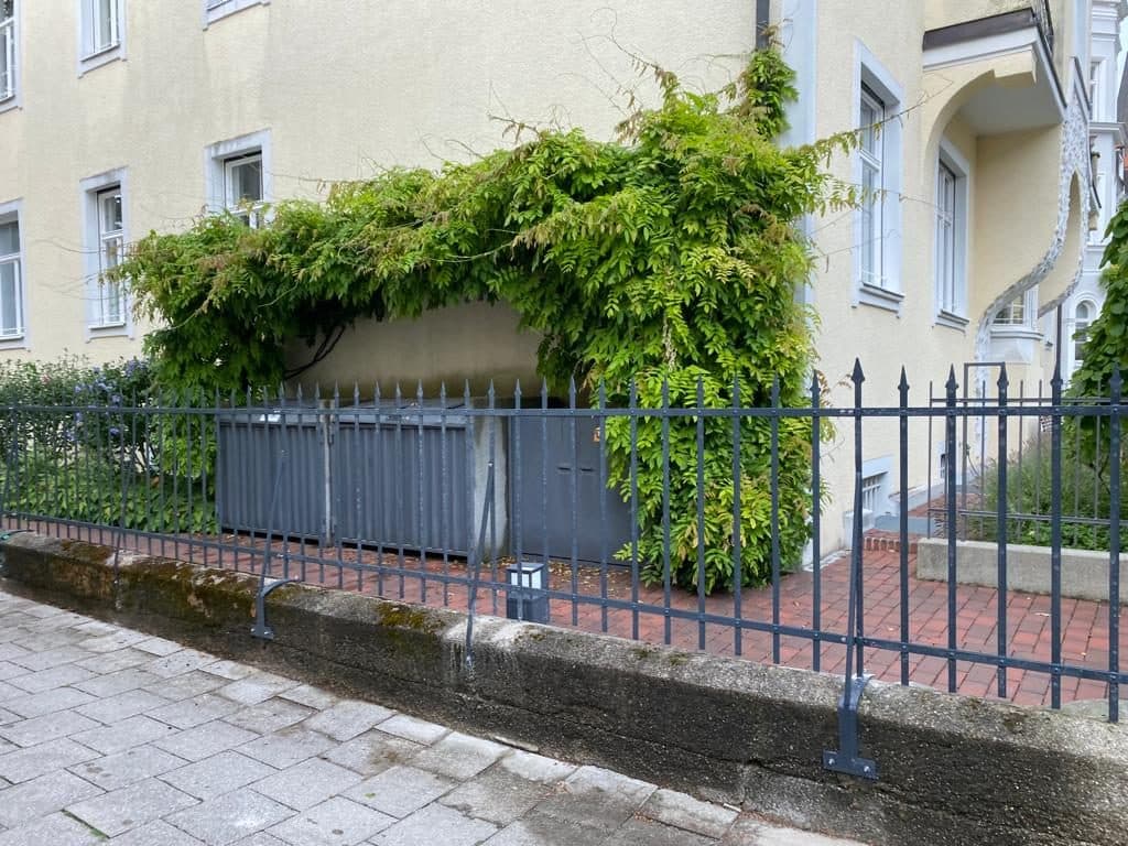 Metallzaun auf einer niedrigen Mauer vor einem Altbau