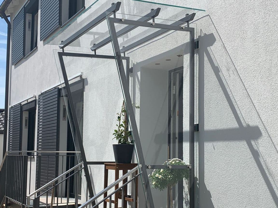 Glasvordach und Metallgeländer an einem Hauseingang