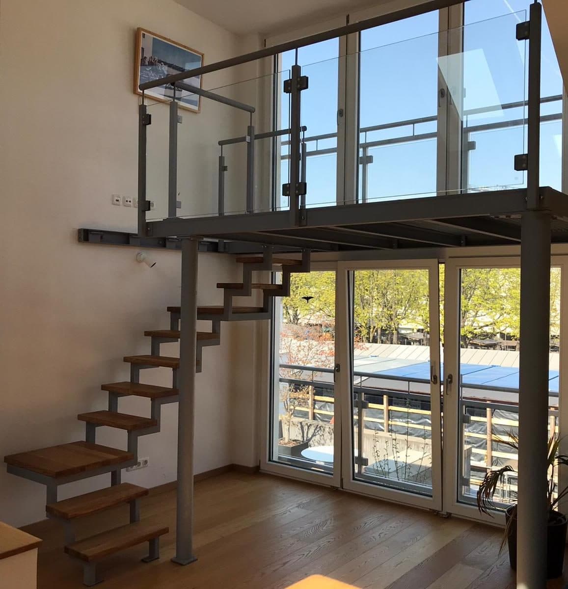Offene Metalltreppe mit Holzstufen und Glasgeländer im Wohnraum