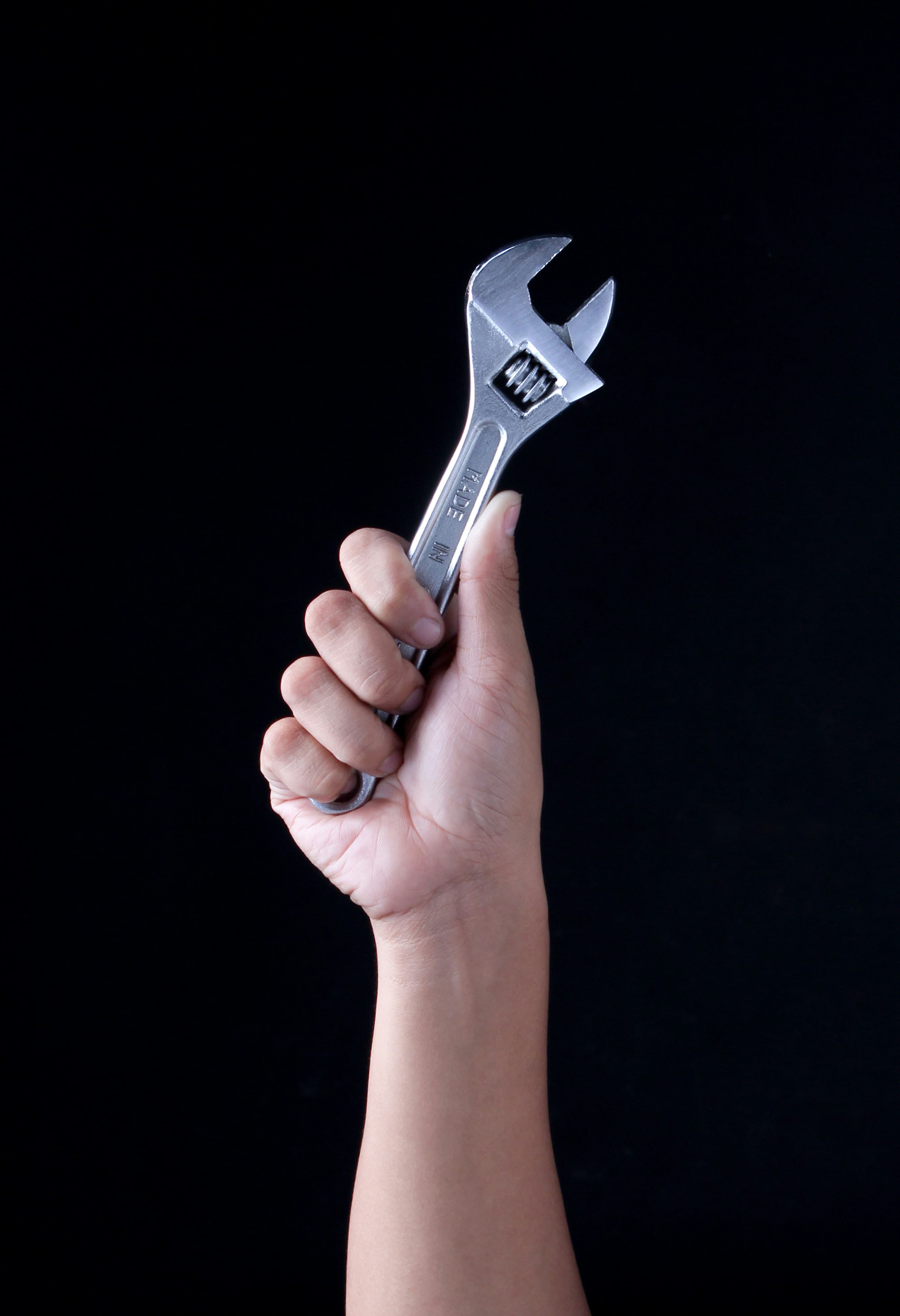 Hand mit Schraubenschlüssel bei der Einstellung eines Metallbauteils