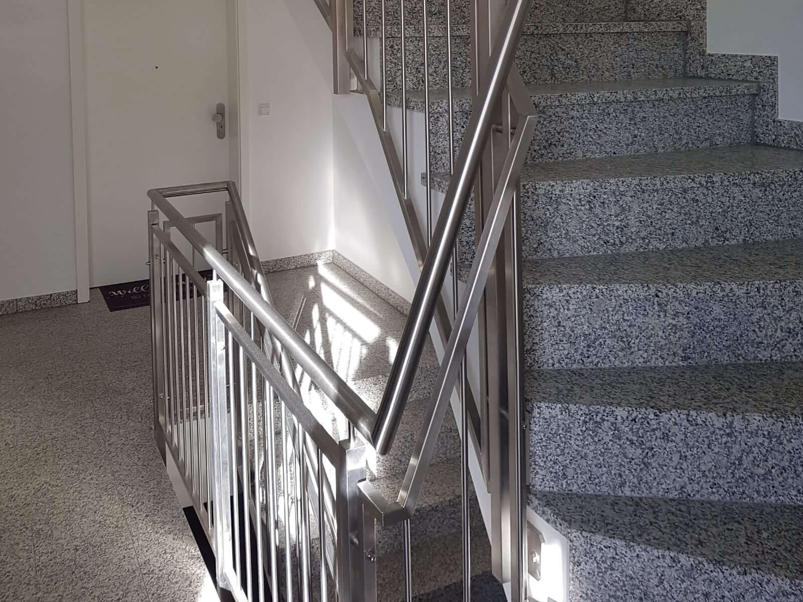 Metallgeländer mit Rundstäben an einer Steintreppe im Innenbereich