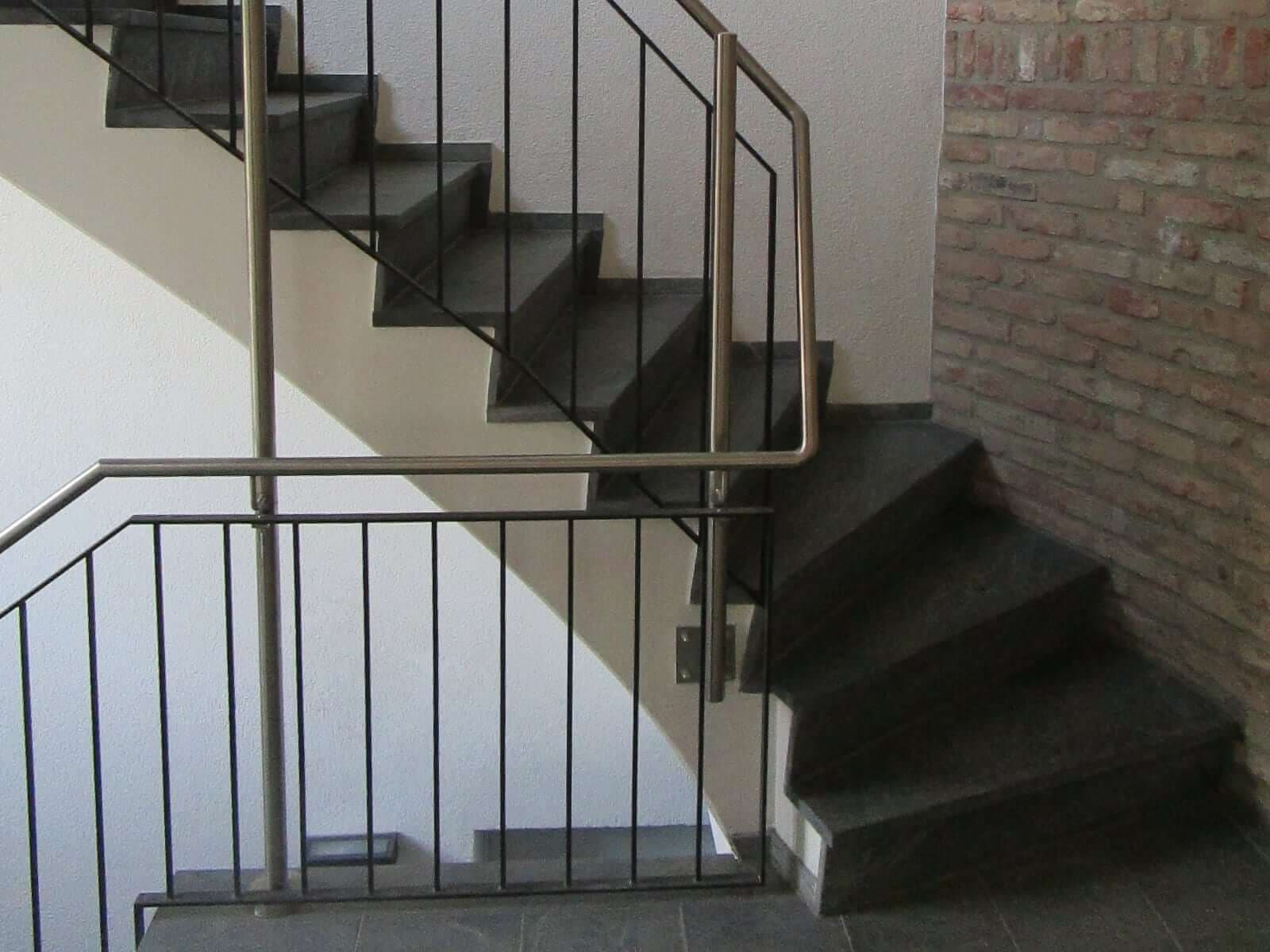 Innengeländer aus Metall an einer Steintreppe neben Sichtmauerwerk