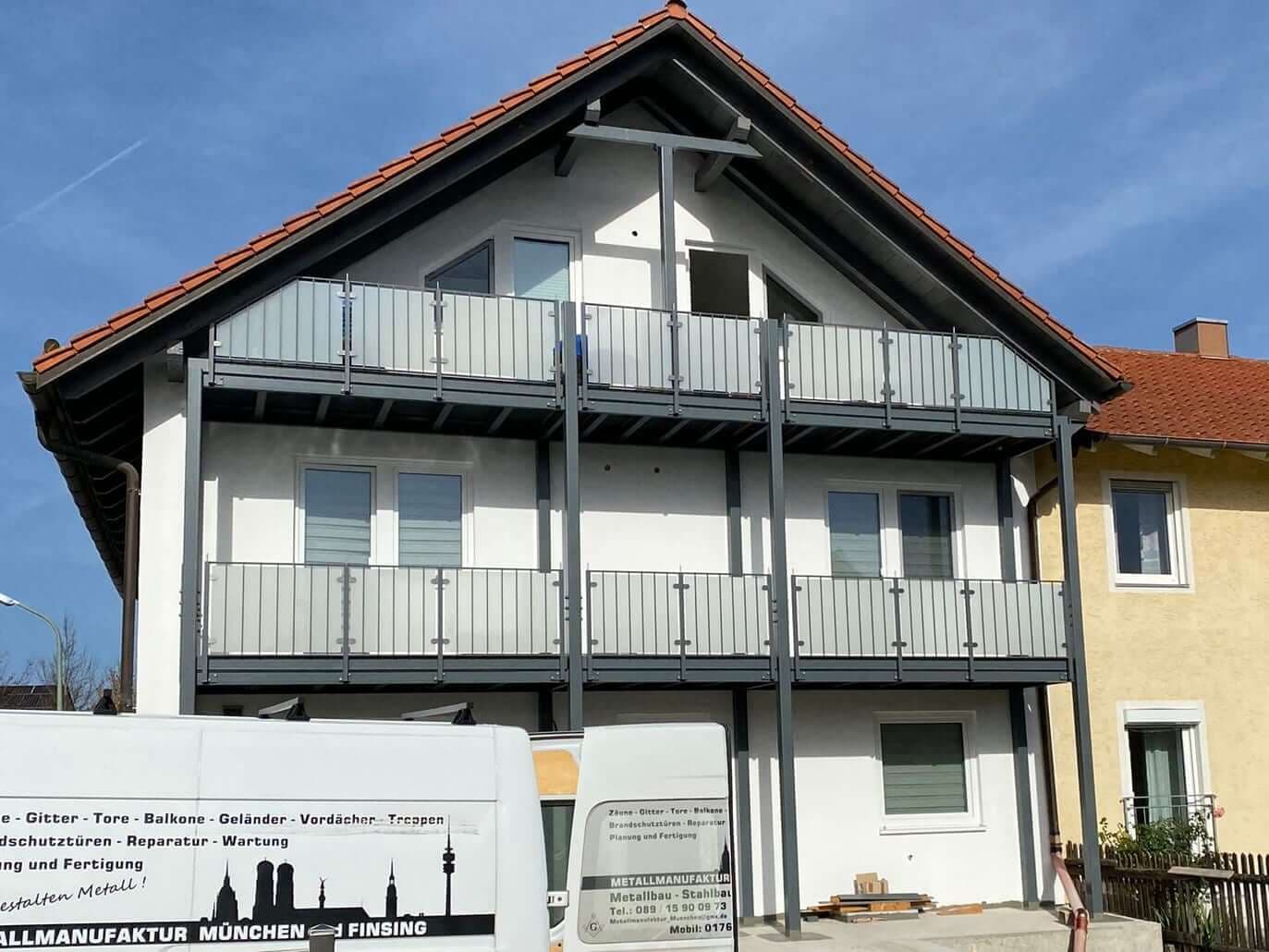 Firmenfahrzeug der Metallmanufaktur vor einer Balkonanlage mit Glasgeländer