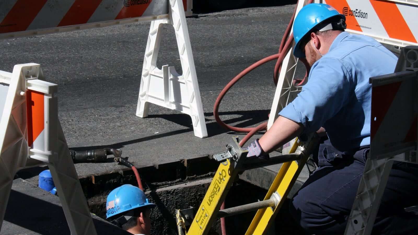 Arbeiten an einem geöffneten Schacht im Straßenbereich