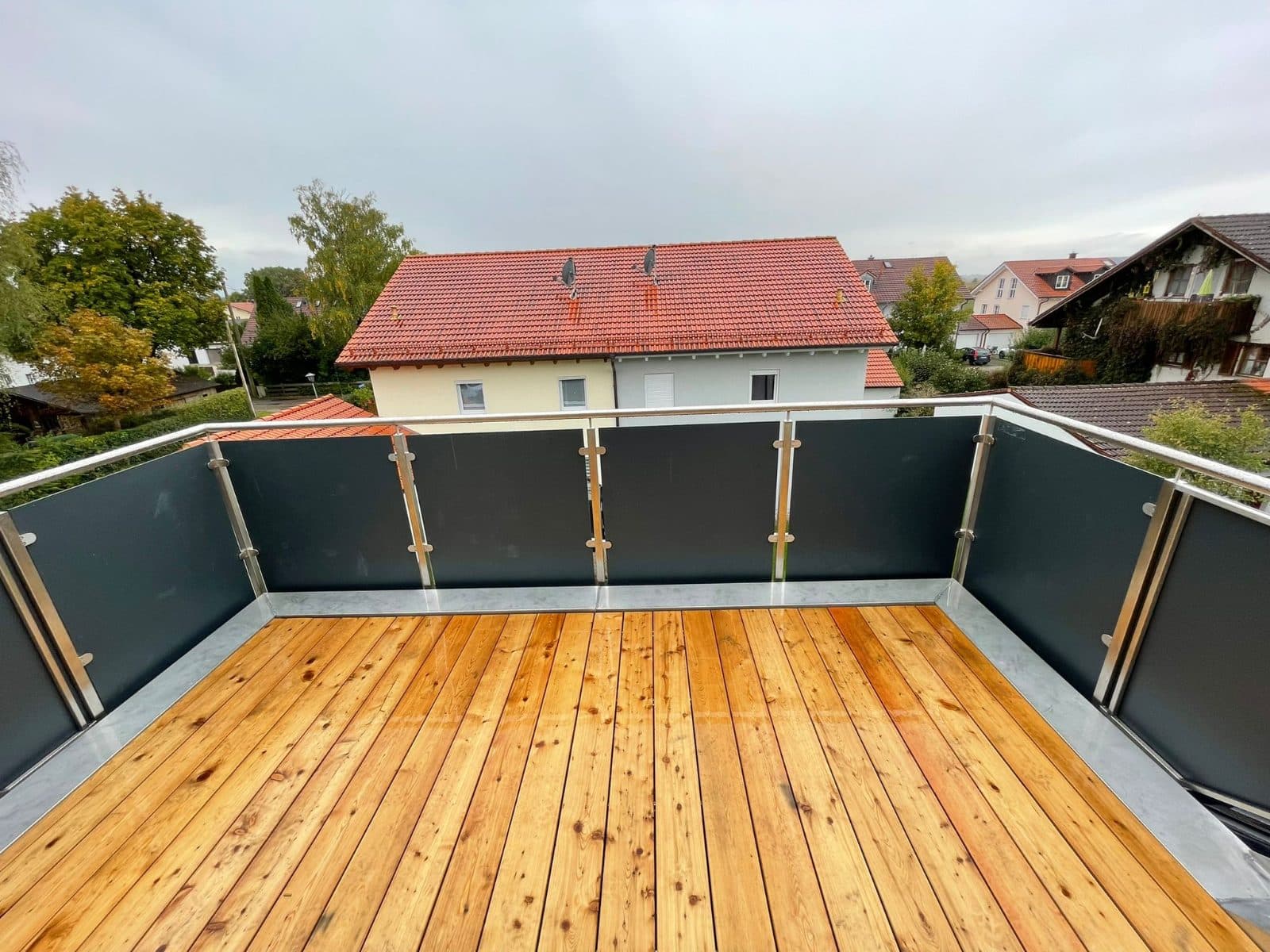 Balkon mit Holzboden und dunkel gefülltem Metallgeländer