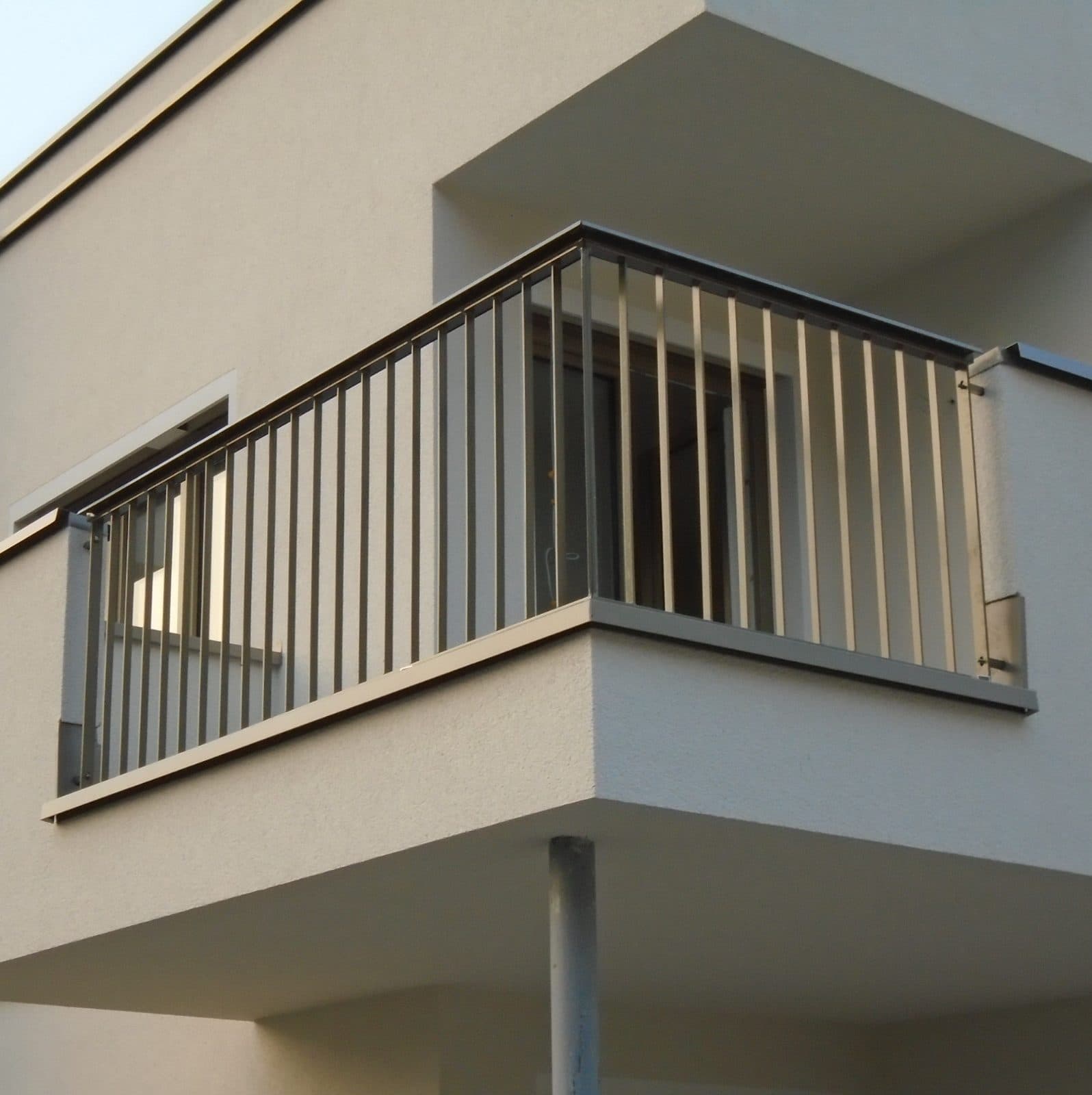 Balkon mit grauem Stabgeländer an einem Neubau