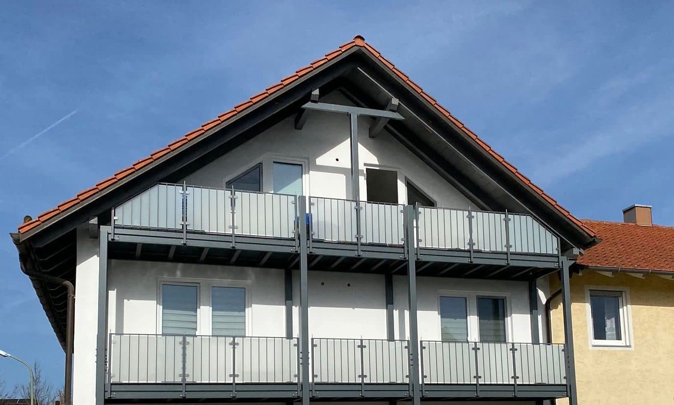 Zwei übereinanderliegende Balkone mit Metall- und Glasgeländern