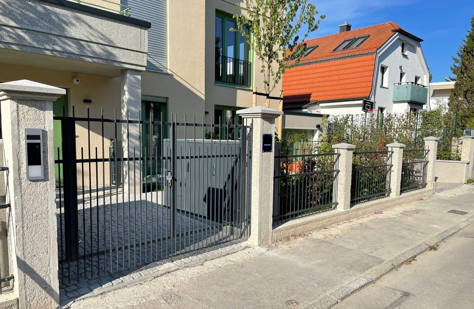Anthrazitfarbener Stabzaun mit Pforte und Schiebetor vor einem Einfamilienhaus