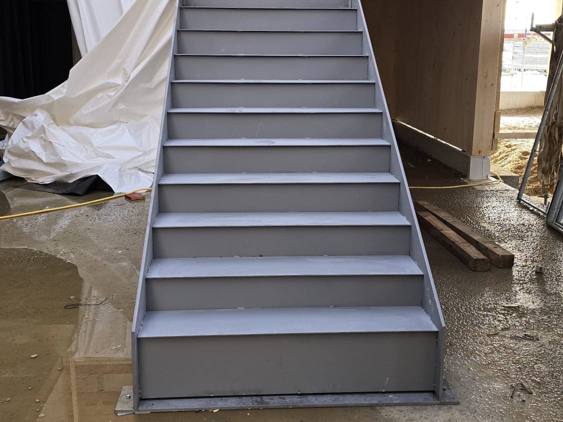 Gerade Metalltreppe mit geschlossenen Stufen in einem Gebäude-Rohbau.